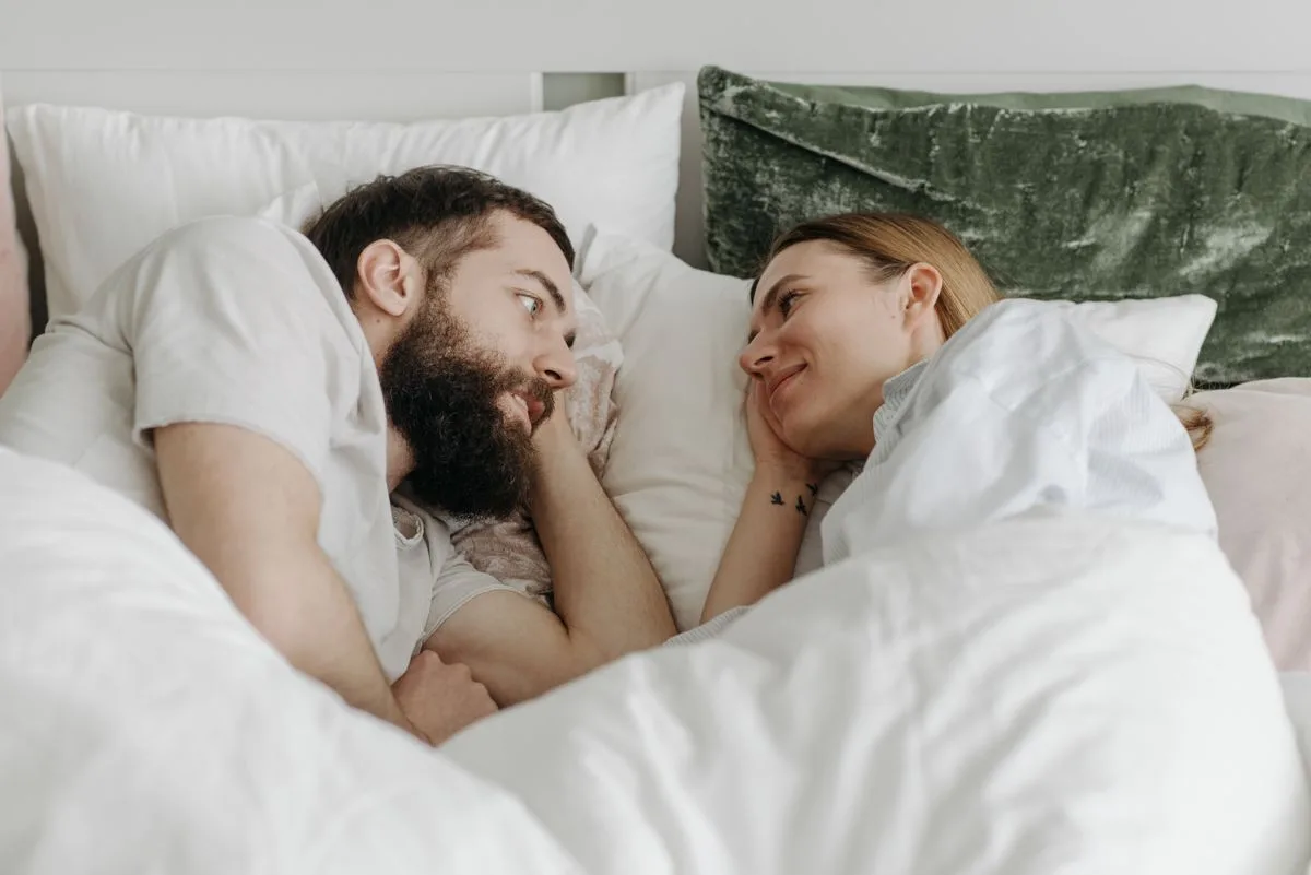 Un couple complice, allongé dans son lit le soir